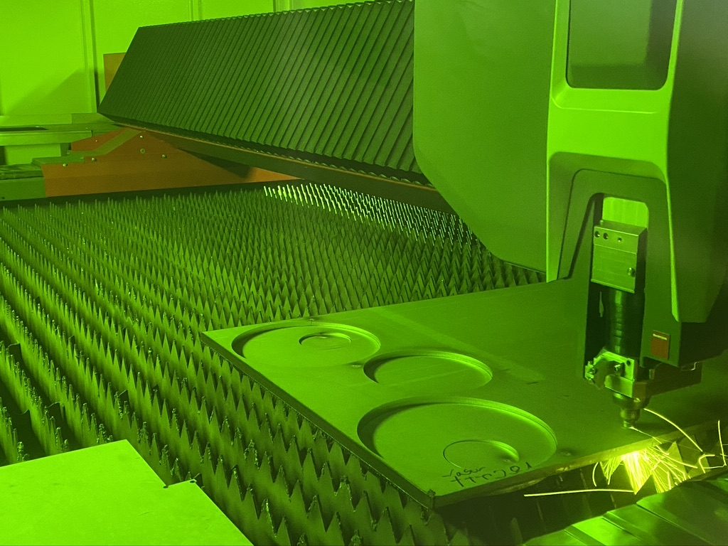 Faserlaser schneidet Ausschnitte aus einer Edelstahltafel, Funkenflug am Schneidkopf