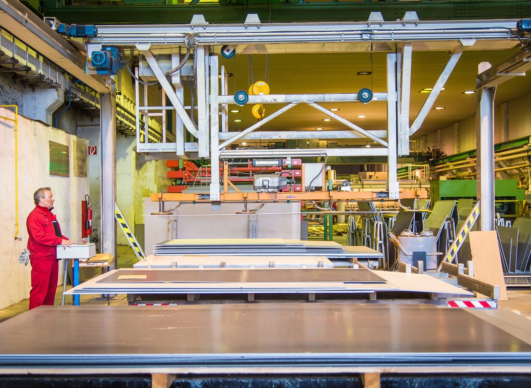 Mitarbeiter steuert die Vakuum-Traverse beim Stapeln großformatiger Edelstahltafeln